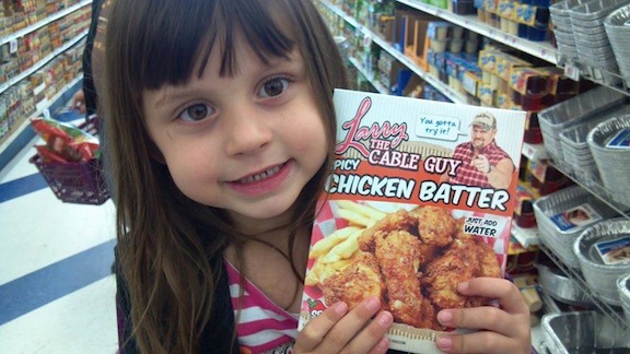 A girl poses with a package of Larry the Cable Guy Chicken Batter.